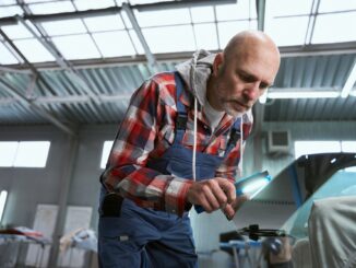 Man in work clothes works with a car detail