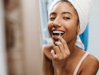cheerful woman cleaning teeth with flosser